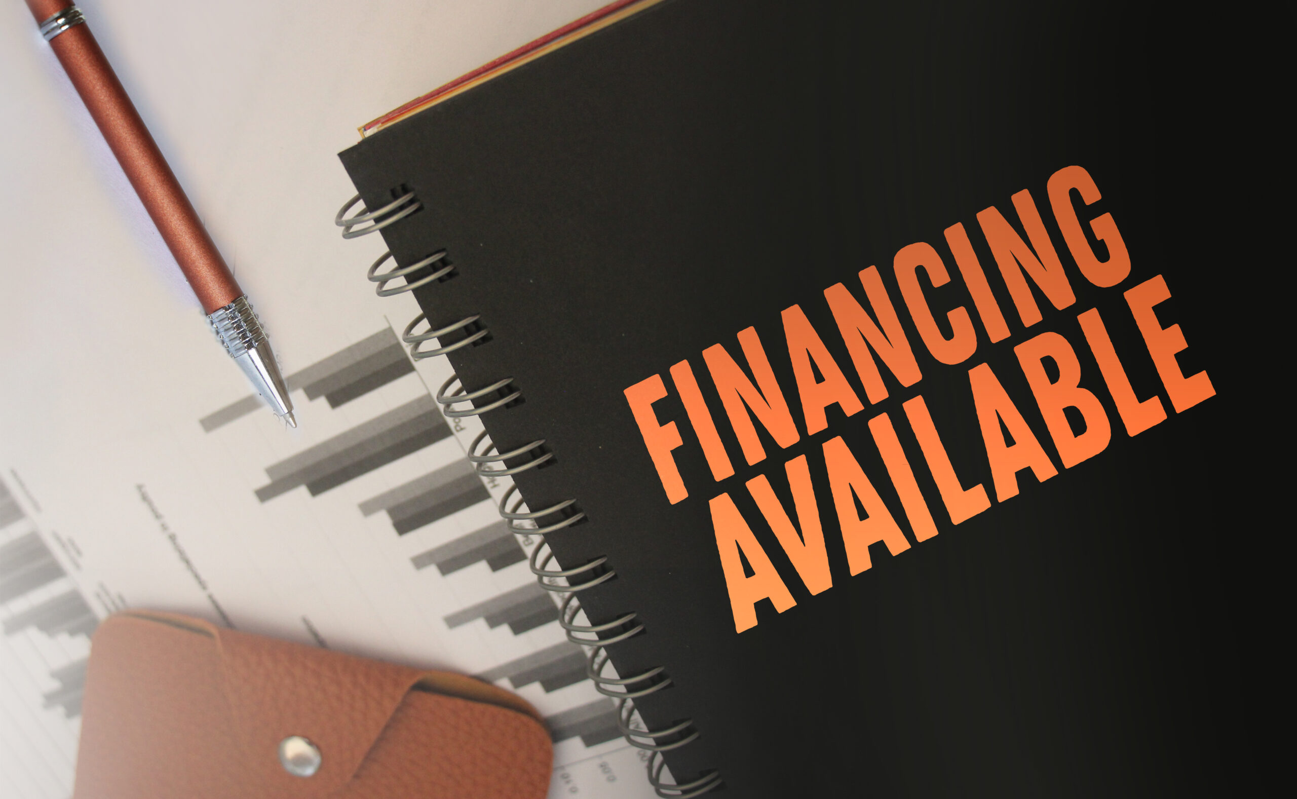 Text financing available in copybook, financial report and brown leather wallet on wooden table. Business financial concept